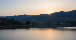 Ambiance de voyage évoquant Paris : lac au lever du soleil au milieu de collines
