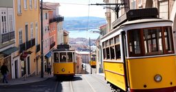 Tramway jaune dans une rue en pente de Lisbonne avec vue sur le Tage